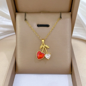 Close-up of gold cherry necklace with red and white crystal hearts in a gift box