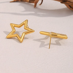 Macro view of 18K gold plated stainless steel hollow star stud earrings on light texture