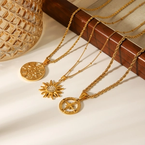 Three gold stainless steel necklaces with sun and heart pendants in macro detail