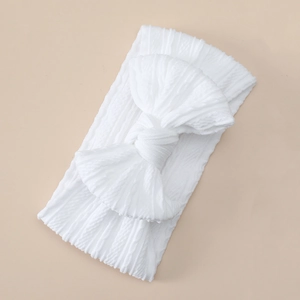 Close-up of white cable knit baby headband featuring a large soft bow detail