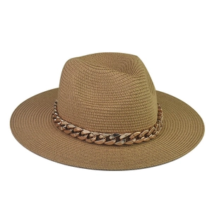 Detailed view of khaki woven straw hat with a bold gold chain band on white background