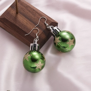 Close-up of green Christmas bulb earrings with gold glitter stars on pink silk background