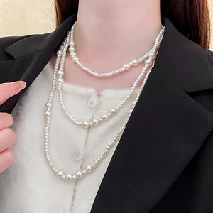 Elegant multi-layer pearl necklace shown on a model wearing a black blazer and white knitwear