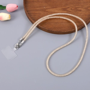 Close-up of golden woven mobile phone lanyard with metal clasp on a wooden tray