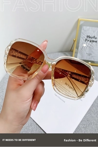 Detail of female hand holding vintage oversized sunglasses with gradient tea lenses