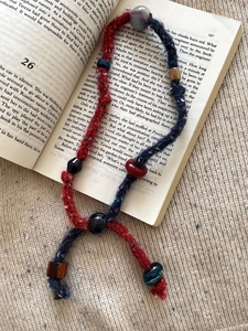 Detail showing woven cotton cord and resin beads on an open book background