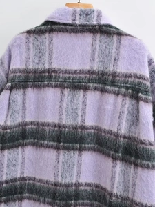 Close-up of fuzzy purple and grey plaid wool fabric texture on a warm winter coat