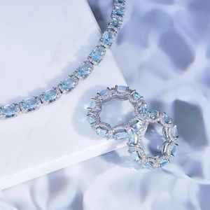Luxury silver jewelry set with aquamarine oval stones on white marble background