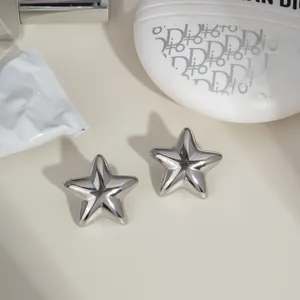 Close-up of minimalist star-shaped silver stud earrings with a polished mirror finish
