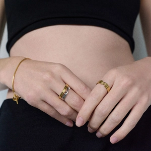 Détails d'un bracelet serpent doré et de bagues en métal portés par un mannequin