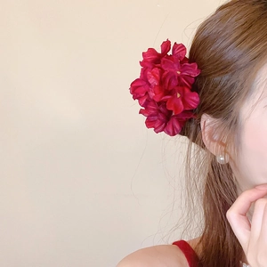 Detail of dark red fabric flower hair clip styled on elegant brown hair side view