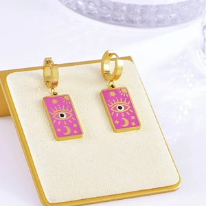 Detail of gold rectangular earrings with pink enamel, evil eye, and star-moon motifs