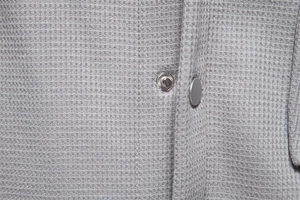 Detail of grey waffle fabric texture and premium metal snap button on men's cardigan