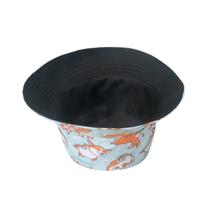 Close-up of a blue bucket hat with cute Corgi prints and a black reversible lining