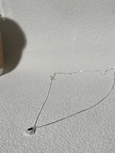 Detail shot of a minimalist S925 sterling silver necklace featuring a teardrop pendant