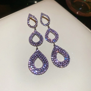 Detailed close-up of triple purple teardrop earrings with shimmering rhinestones and silver base