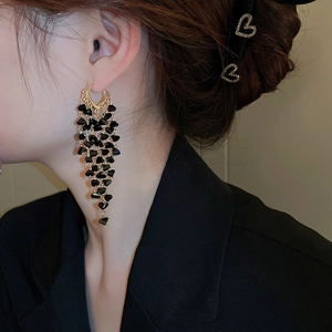 Close-up of elegant black beaded tassel earrings with gold finish on model