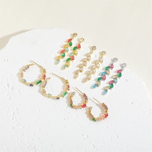Luxurious gold earrings set with colorful zircon stones on a white stone background
