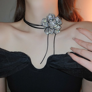 Detail of a black choker necklace featuring a large sparkling rhinestone flower pendant
