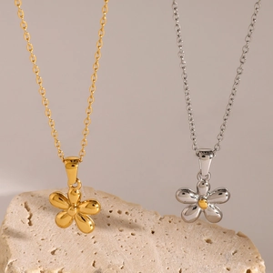 Elegant gold and silver flower pendant necklaces on minimalist stone display