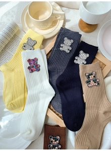 Detail showing knit cotton socks with crystal bear charm on rib textured fabric