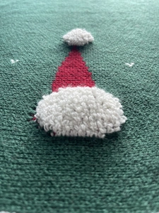 Vue macro de la jupe de sapin tricotée verte avec motif de bonnet de Noël en 3D
