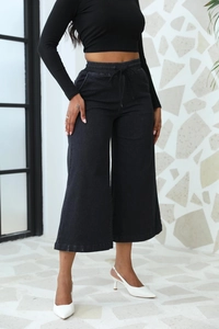 Gros plan d'un pantalon noir à jambes larges avec taille élastique à cordon et coupe évasée