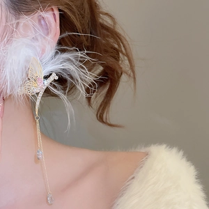 Detailed close-up of a long tassel butterfly earring with white feathers and rhinestones