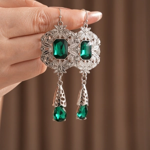 Macro shot of vintage silver earrings with emerald green gemstones and hollow engraving