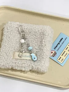 Macro shot of blue beaded phone strap with shell pendant and fish charm on soft fabric