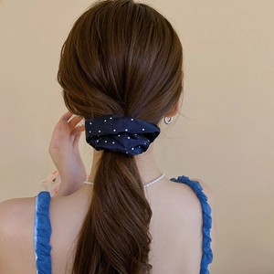 Detail of a large navy blue polka dot fabric scrunchie on a ponytail for hair styling