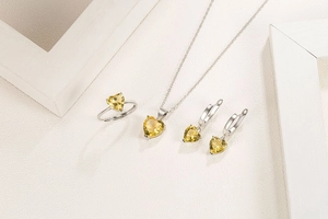 Elegant jewelry set with yellow heart zircon pendant necklace, earrings and ring on beige backdrop