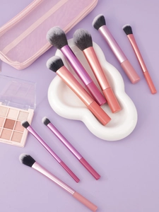 Détail de 8 pinceaux de maquillage aux manches métallisés et pochette de rangement rose