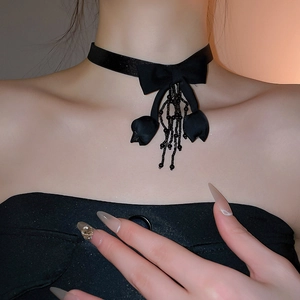 Close-up of elegant black velvet choker with bow and bead tassels on a model