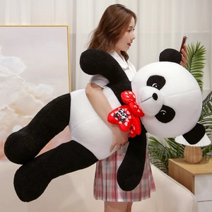 Macro view of large plush panda toy with soft black and white fur and red bow tie