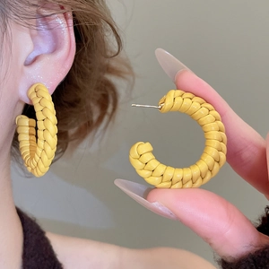 Detailed view of yellow hand-woven leather texture on minimalist C-shaped hoop earrings