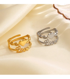 Close-up of gold and silver layered Love rings displayed on elegant beige silk fabric