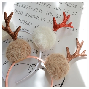 Macro detail of glittery reindeer antlers and soft plush balls on festive Christmas headbands