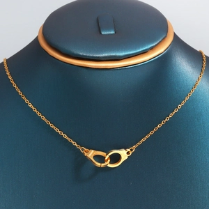 Dettaglio della collana a manette dorate con incisione freedom su metallo lucido di classe