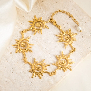 Elegant gold stainless steel bracelet featuring spiral sun links and a pearl charm