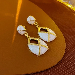 Détail de boucles d'oreilles vintage en forme de goutte dorée sur fond en cuir brun
