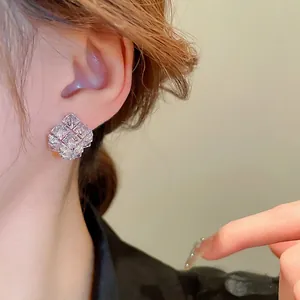 Silver square stud earrings with sparkling cubic zirconia on female model ear