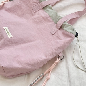 Detail of pink nylon tote with Sashiken label, green lining, and woven rope charm
