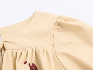 Detail showing the intricate red embroidery and cotton-linen texture on the neckline