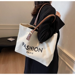 Canvas-Einkaufstasche mit Fashion Paris-Druck und Ledergriffen, am Modell getragen