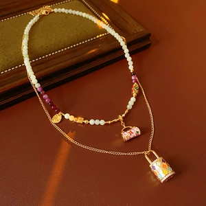 Detail of vintage enamel basket pendants and layered gold chain on leather background