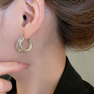 Macro shot of elegant silver double-layer hoop earrings with shimmering crystals on model