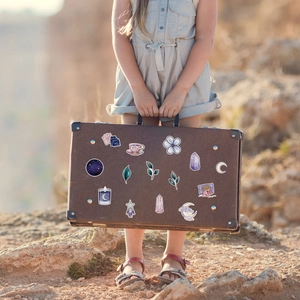 Girl holding vintage suitcase with colorful waterproof magic doodle stickers in nature