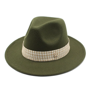 Macro detail of dark olive wool fedora with woven band and gold metal M charm