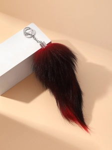 Detail of red and black gradient faux fur fox tail keychain with silver metal clip